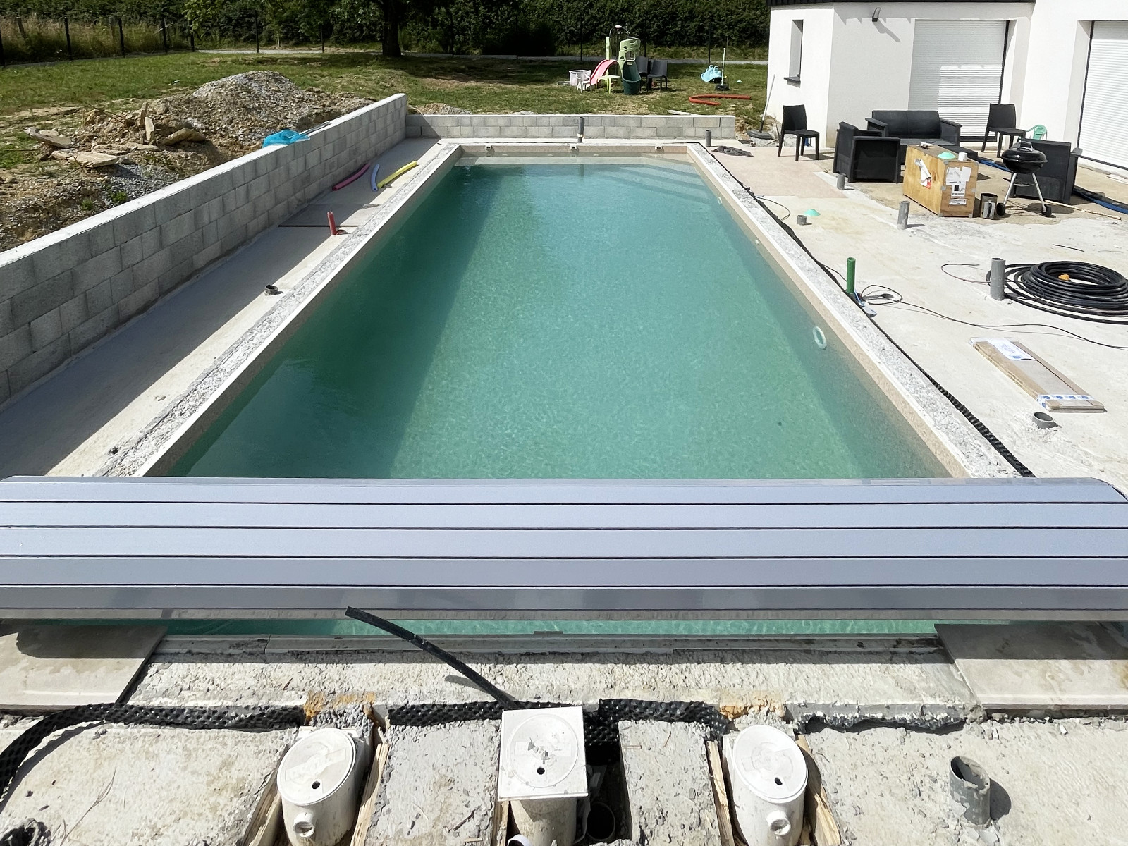 Piscine rectangulaire en eau, bordée d’une terrasse en cours d’aménagement