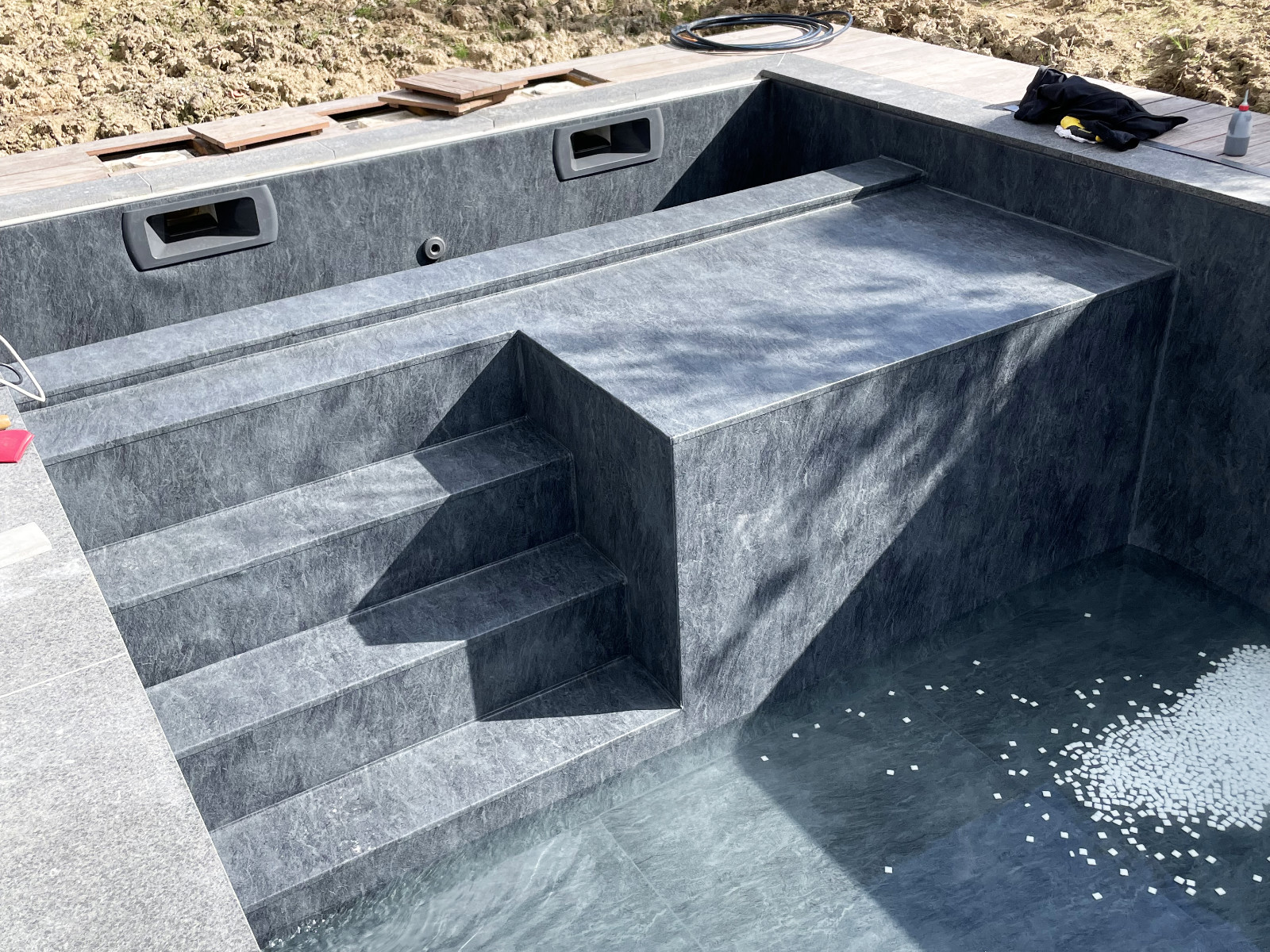 Marches et banquette de piscine habillées d’une membrane armée grise